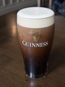 Guinness pint on table at Patrick Johnny Sally’s pub, with creamy head and dark stout in warm interior