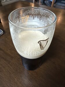 Guinness pint at Patrick Johnny Sally’s pub on a wooden table with creamy head and dark stout