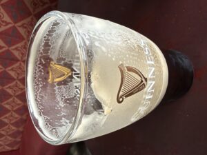 Half empty pint glass of Guinness with lacing and foam residue