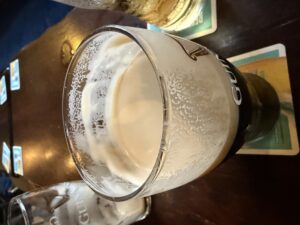 A pint of Guinness in a half-empty glass showcasing its lacing
