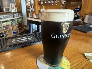 Guinness beer on a wooden table with a coaster and beer taps in the background