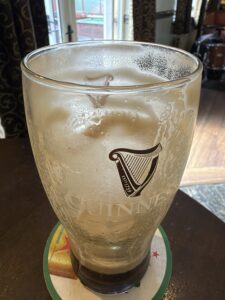 Creamy head of freshly poured Guinness with harp logo and golden beer in branded glass at Annora Bar, Portnoo