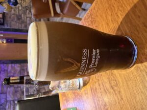 Guinness pint at The Castle, Belturbet with a creamy dome and Premier League tulip glass on a pub table