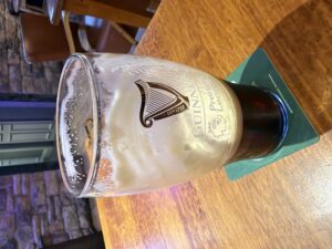 Half-finished Guinness pint at The Castle, Belturbet, on a wooden pub table in a cozy restaurant setting
