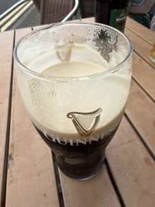Close-up of a nearly finished Guinness pint with creamy foam on a wooden patio table at the Beach Hotel in Mullaghmore