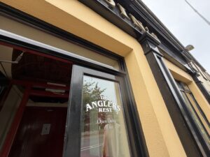 Exterior entrance of The Anglers Rest pub in Kinlough, with black trim and open doorway